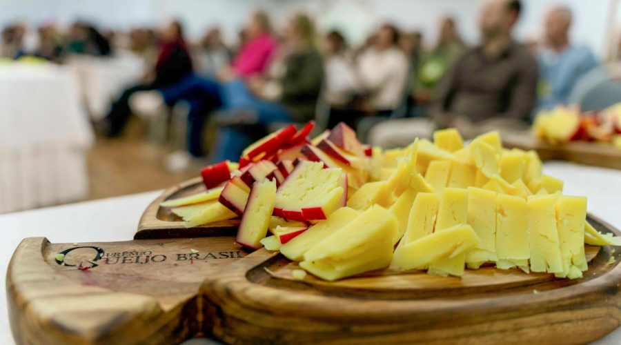 Tábua de queijos e ao fundo alunos da Formação Queijista, no Festival Queijo Brasil 2025. Foto: Wartung Produtora.